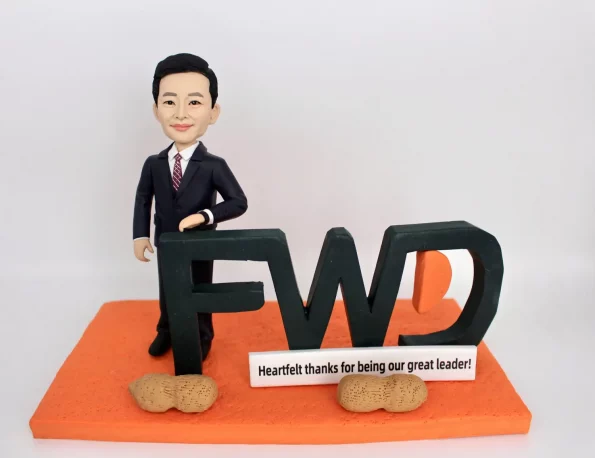 一尊為FWD公司領導訂製的人像公仔。他身穿西裝，手靠在大型FWD標誌上。橙色底座上有兩顆花生模型，因為這是他個人最喜歡的零食，這份充滿個人心思的禮物，也寓意著『好事發生』