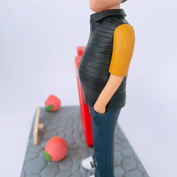 一個戴眼鏡、身穿黃衣黑色背心的人像公仔，站在灰色地台上，旁邊有大型紅色「70」字樣和兩個壽桃，前方有祝福字牌。