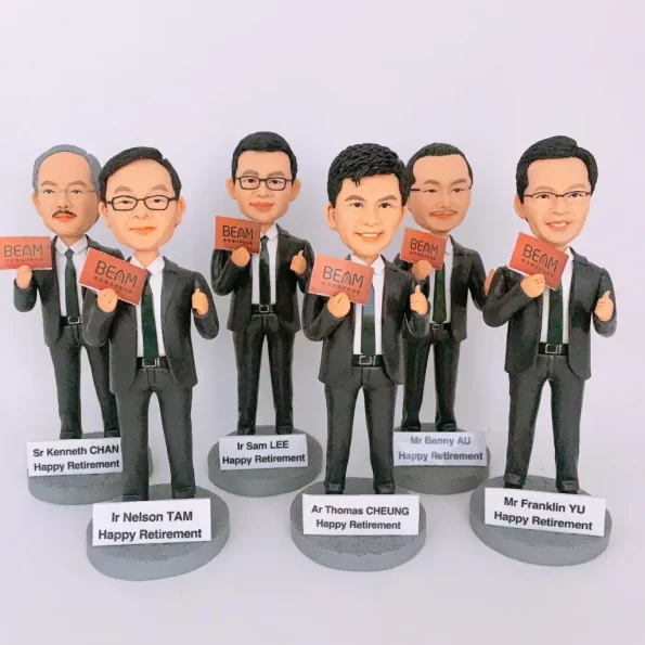 一套六個為 BEAM 綠建環評團隊成員訂製的榮休人像模型。六位男士均身穿黑色西裝及綠色領帶，一手豎起大拇指，另一手拿著印有 BEAM 標誌的紅色卡片。每個模型都站在刻有各自姓名及『Happy Retirement』祝福語的獨立底座上。