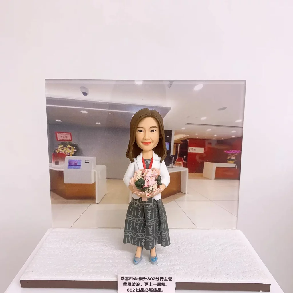 一款以女性為主的人像公仔，手捧花束，穿著白色外套和印花裙，背景為現代辦公室接待區。這件作品適合作為升職禮物、上司禮物或公司禮物，強調辦公室背景與慶祝氛圍。