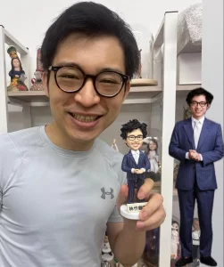 這份為林作先生訂製的人像公仔，連招牌笑容的弧度都幾乎還原，雙手交叉的姿態盡顯其自信。這證明了我們團隊不僅追求外形相似，更致力於捕捉人物的獨特氣場。