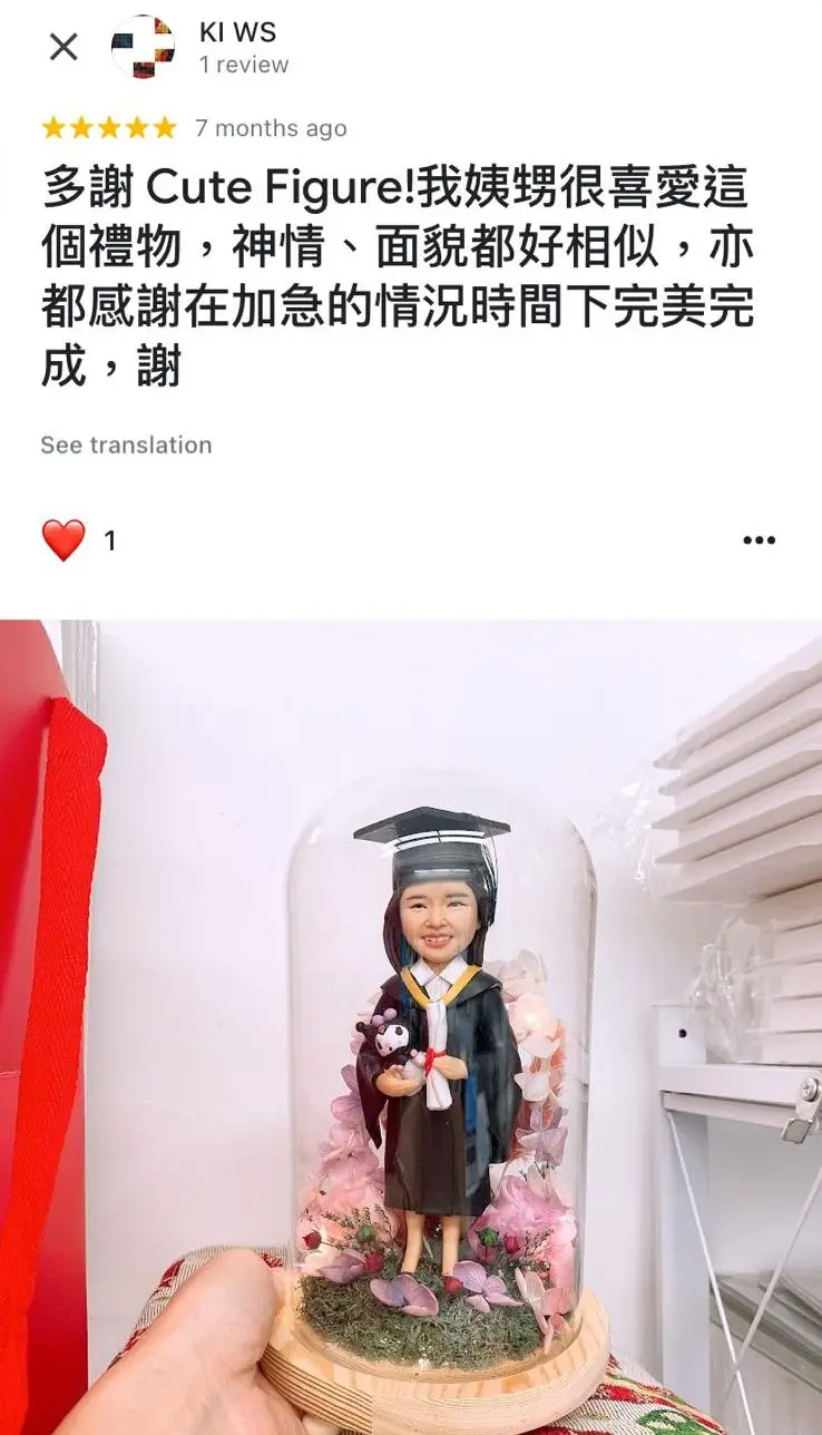 一件送給姨甥女的畢業禮物。一個女性畢業生人像公仔,身穿畢業袍,手持證書和玩偶,被放置在一個充滿粉色永生花的玻璃罩中,設計精緻而夢幻。