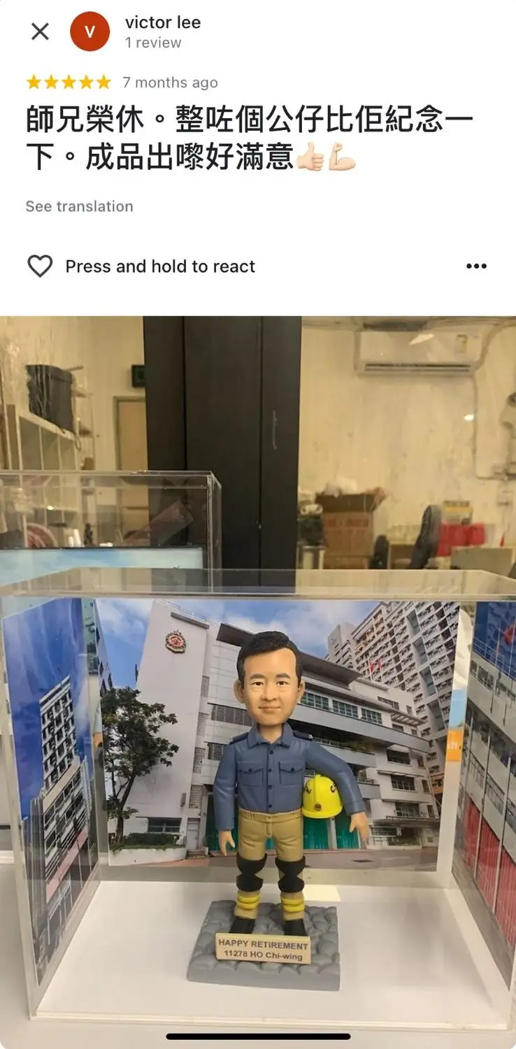 一件送給消防員師兄的榮休禮物。一個男性人像公仔,身穿消防員工作服,手持黃色頭盔,面帶微笑。公仔的背景是他的消防局照片,底座上刻有他的姓名和「HAPPY RETIREMENT」字樣,極具紀念價值。