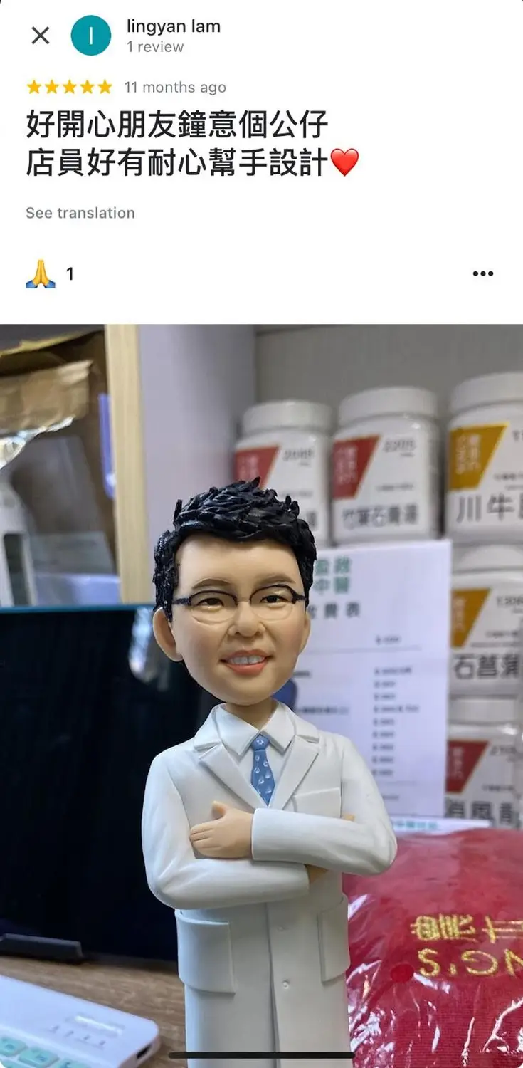 一件送給中醫師的榮休禮物。一個戴眼鏡的男性人像公仔,身穿白色醫師袍,雙手抱胸,面帶親切微笑。背景是中藥房的藥櫃,擺滿了藥材瓶,突顯其專業身份。