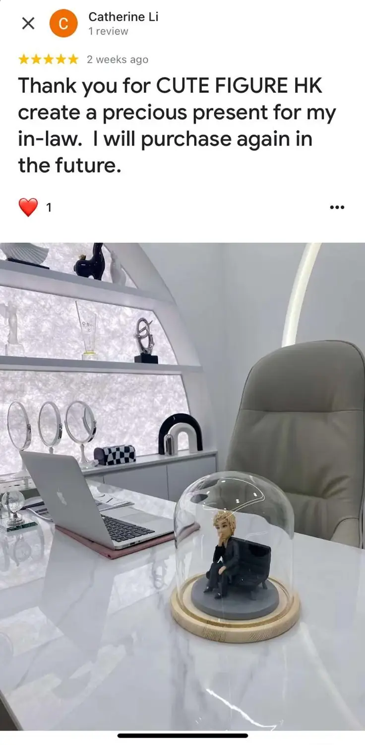 一件贈予 in-law 的精緻人像公仔禮物。一個金髮人像公仔,身穿黑色套裝,坐在沙發上托腮沉思,整個作品被放置在一個永生花擺設的玻璃罩中。