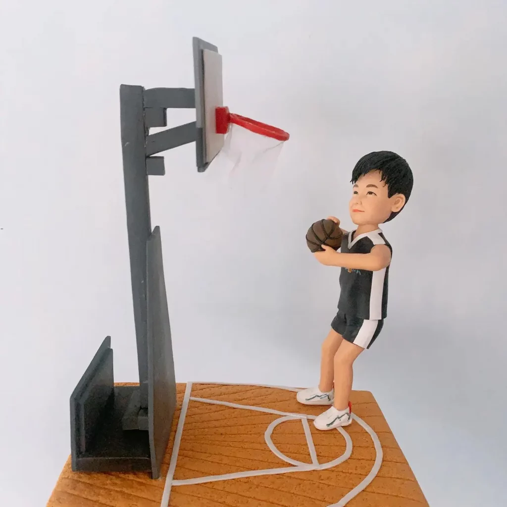 一位男士的籃球運動公仔，他站在微縮木地板球場上，做出準備投籃的姿勢，瞄準著籃框。