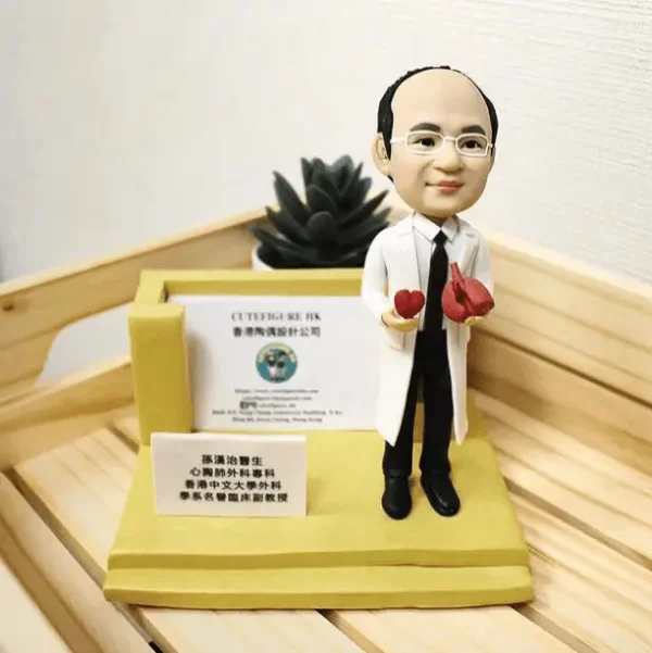 一位醫生造型的人像公仔，手持心臟模型，旁邊有名牌和醫療相關展示架