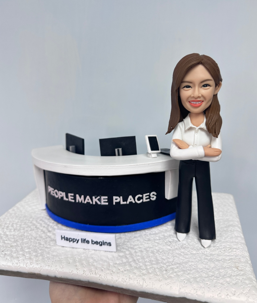 一款女性人像公仔，穿著白色襯衫和黑色長褲，雙手抱胸自信微笑，站在立體公司前台背景前，前台寫有「PEOPLE MAKE PLACES」字樣，底部有「Happy life begins」標語。這款人像公仔適合作為升職禮物、上司禮物或公司禮物，強調立體背景設計。