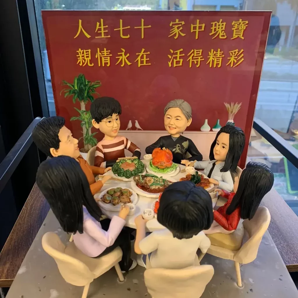 一組人像公仔圍坐在圓桌旁共享豐盛飯菜，背景有紅色賀詞板和窗外城市景色，展現大家庭團聚的溫馨氛圍。