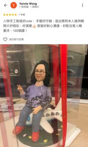 一張來自顧客Yonnie Wong的五星評價截圖。評價內容稱讚人像公仔「手工製造好cute，手藝好仔細」，與真人照片非常相似，並對客服的耐心溝通和配合表示「100個讚」。附圖展示了一份極具心思的榮休禮物：一位戴眼鏡的長髮女士，面帶微笑地坐在飛機模型上並舉起V字手勢，象徵著開展新的旅程。