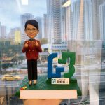 一款為富邦銀行(Fubon Bank)「G3」團隊成員訂製的人像公仔，作為一份慶祝成功的禮物，公仔雙手豎起大拇指，自信地站在團隊標誌旁，背景是辦公室外的城市景觀。
