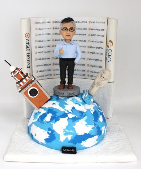 一款慶祝男士退休的人像公仔，他站在地球模型上，背景是公司LOGO背景牆，旁邊還有香港鐘樓和新加坡魚尾獅的立體建築物模型。