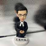 一款男性律師人像公仔，身穿律師袍，站立在刻有「天道酬勤」銘牌的底座上，是送給律師的完美入職禮物。