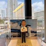 一款為香港警務人員訂製的晉升人像公仔，公仔身穿白色警官制服，背景為警察戰術訓練大樓，用以祝賀其榮陞之喜。