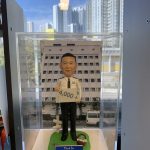 一款為香港警務人員訂製的退休人像公仔，主角為一名警官，身穿白色督察級制服，背景為中區警署，由其下屬為祝賀其2025年光榮退休而敬贈。