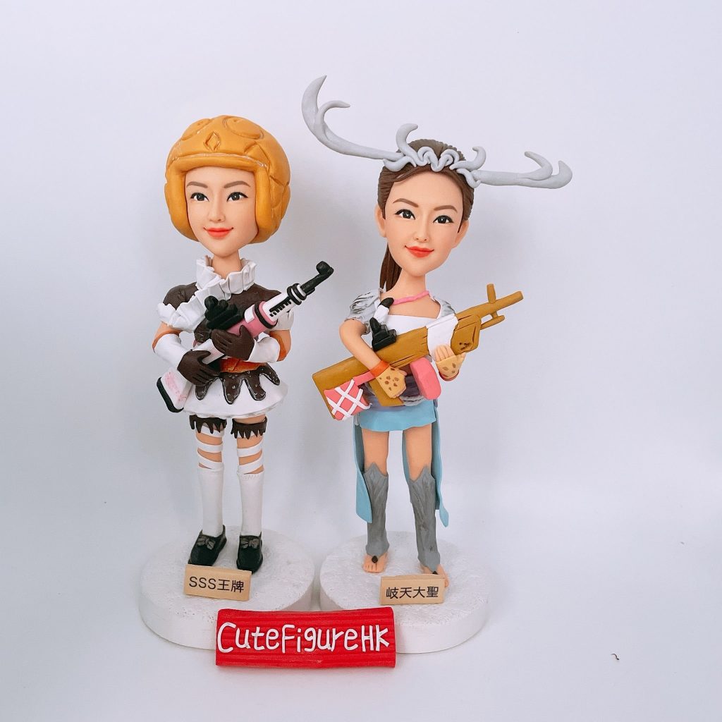 兩款女性遊戲玩家的訂製人像公仔,她們身穿遊戲角色服裝,手持槍械武器,底座上分別刻有中文遊戲稱號「SSS王牌」和「岐天大聖」。