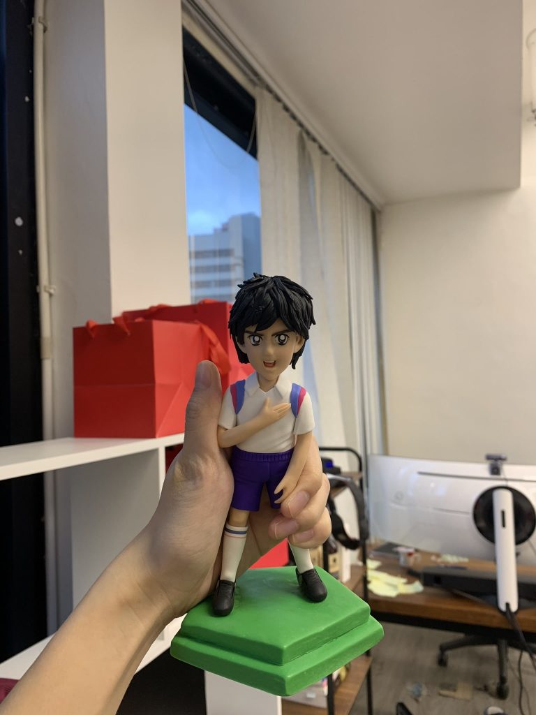 一款根據經典動漫人物《足球小將》戴志偉製作的人像公仔,公仔身穿球衣,手撫胸口,是送給粉絲的完美生日禮物。