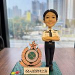 「香港海關人像公仔，身穿白色制服襯衫與黑色長褲，雙手交叉胸前，神情自信專業。底座展示『Hong Kong Customs and Excise』徽章，以及『祝 Ivy 姐榮休之喜』字樣，象徵此公仔為慶祝香港海關職員榮休（退休）特別訂製的專屬紀念禮物。此公仔細節精緻，適合作為榮休禮物、警察或海關紀念品，以及專屬人像公仔收藏。」