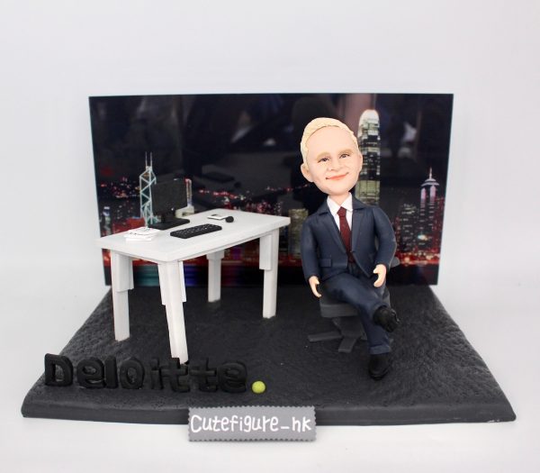 一款為外國老闆訂製的退休禮物人像公仔，公仔是一位穿西裝的男士，坐在辦公室的立體場景中，背景是香港維港背景夜景，底座上有Deloitte公司標誌。