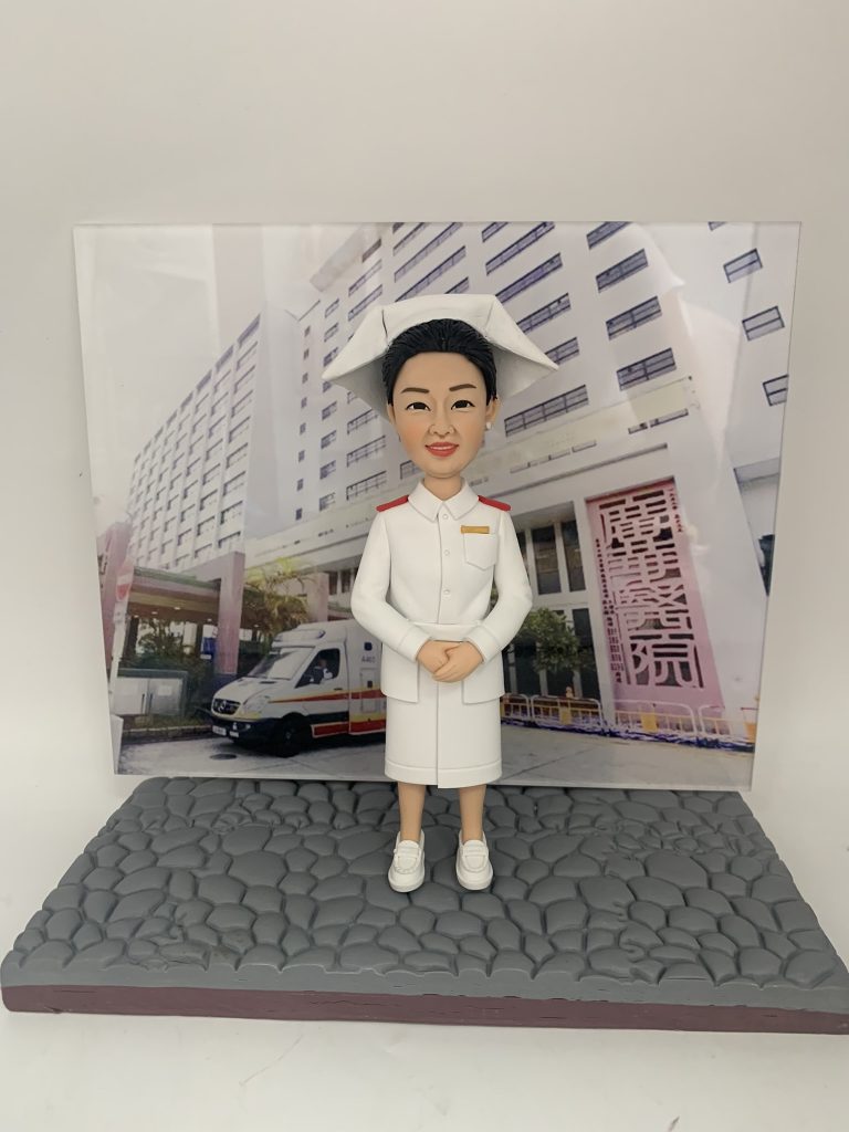 一款為廣華醫院護士訂製的退休禮物。精緻的人像公仔身穿傳統的白色護士服與護士帽，莊重地站立著，背景板是廣華醫院大樓及門前的救護車，是一份完美展現其職業生涯的紀念品。