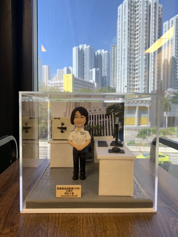 一款為香港女性總督察訂製的榮休人像公仔，場景還原了她的辦公室，並配有書桌、電腦及夾萬等背景配件裝飾。