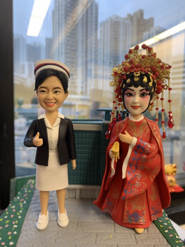 一位護士造型公仔身穿白色制服與黑色外套，頭戴護士帽，細節刻畫展現專業與溫暖特質；另一位戲劇新娘造型公仔身穿紅色婚禮服飾，搭配華麗金色與紅色頭飾，體現戲劇化舞台氛圍。兩款人像公仔均細緻雕刻，極具藝術感與收藏價值，適合作為榮譽表揚與感謝賀禮。