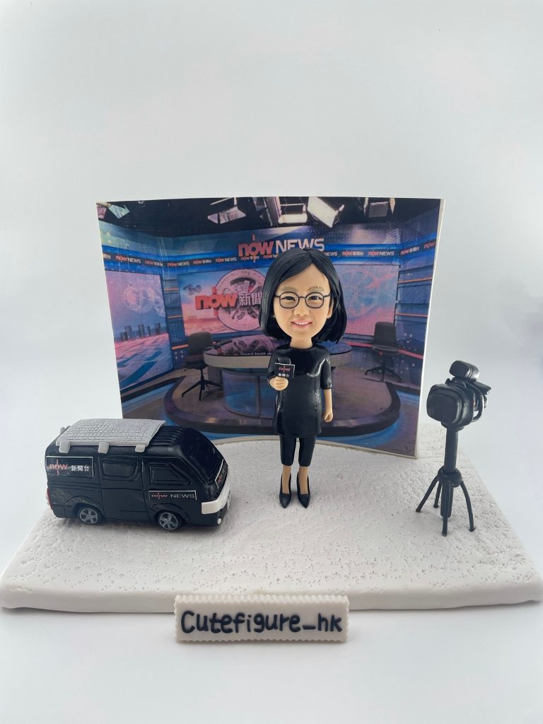 新聞採訪主題人像公仔場景：短髮戴眼鏡的女性記者穿黑色連身裙與高跟鞋，手持麥克風站在白色地台上；左側是一台黑色新聞採訪車模型，右側為架在三腳架上的專業攝影機；背板呈現演播室畫面與節目佈景。整體具專業與儀式感，適合作為新聞記者退休禮物與致敬紀念擺設。