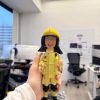 一款為消防員訂製的Q版人像公仔，公仔面帶燦爛開朗的笑容，身穿全套黃色消防制服，站立在刻有個人編號PFn11195的石磚底座上，是一份充滿活力的退休禮物。