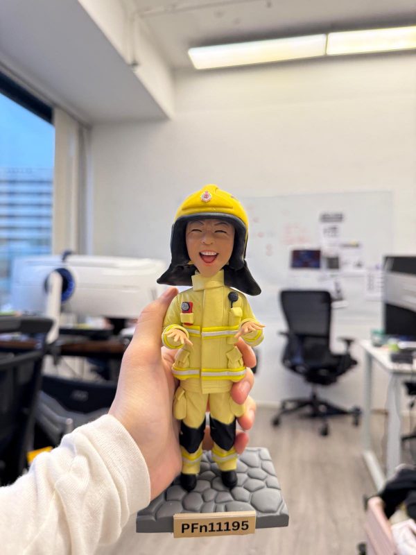 一款為消防員訂製的Q版人像公仔，公仔面帶燦爛開朗的笑容，身穿全套黃色消防制服，站立在刻有個人編號PFn11195的石磚底座上，是一份充滿活力的退休禮物。