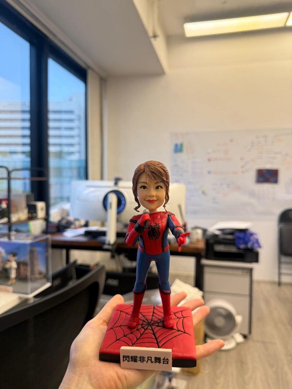 一款將女士頭像與蜘蛛俠身體結合的訂製人像公仔，她身穿蜘蛛俠戰衣，手持咪高峰，站在一個刻有「閃耀非凡舞台」字樣的紅色蜘蛛網地台上。