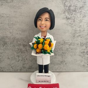 定製醫護人像公仔，角色為實驗室主管 Ms Law Wai Yin，身穿白袍，手捧鮮花，底座刻有「Laboratory Manager」字樣。此公仔象徵醫護專業及實驗室醫生/醫療管理人員的專業身份，是醫院或科研機構專屬的退休與感謝禮物。