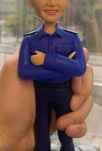 一款為香港消防員訂製的升職人像公仔，公仔身穿藍色工作制服，由其駐守的尖沙咀消防局B隊全體隊員敬贈，祝賀其榮陞。