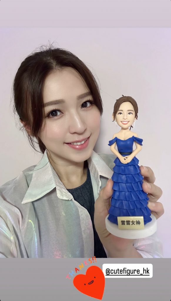 女子手持一個藍色多層荷葉禮服的人像公仔，公仔底座前牌寫有「雪雪女神」字樣；畫面右下角有「THANKS!!」與帳號貼圖。