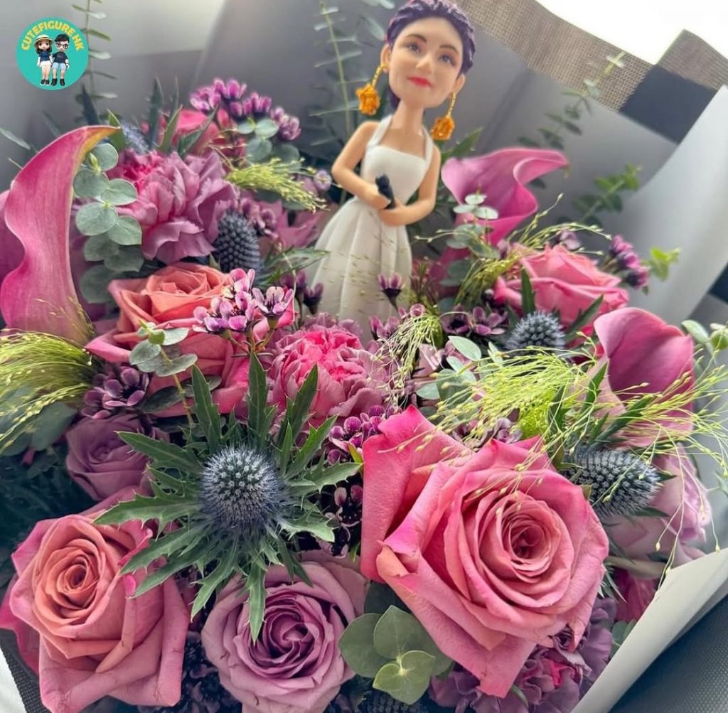 拼圖式畫面展示真人與對應的人像公仔造型對照：左側為一位穿白色長禮服、手持麥克風的舞台表演者，配戴誇張的金色耳飾與編髮造型；右側為同款元素的人像公仔，穿白色無袖長裙，手握黑色麥克風，戴金色耳飾與紫紅色編髮。其他照片中，公仔被置於海報前近拍，以及嵌入大束粉紫色系花束中央（玫瑰、馬蹄蓮、尤加利與葉材）作為花禮擺設，背景可見室外綠景。