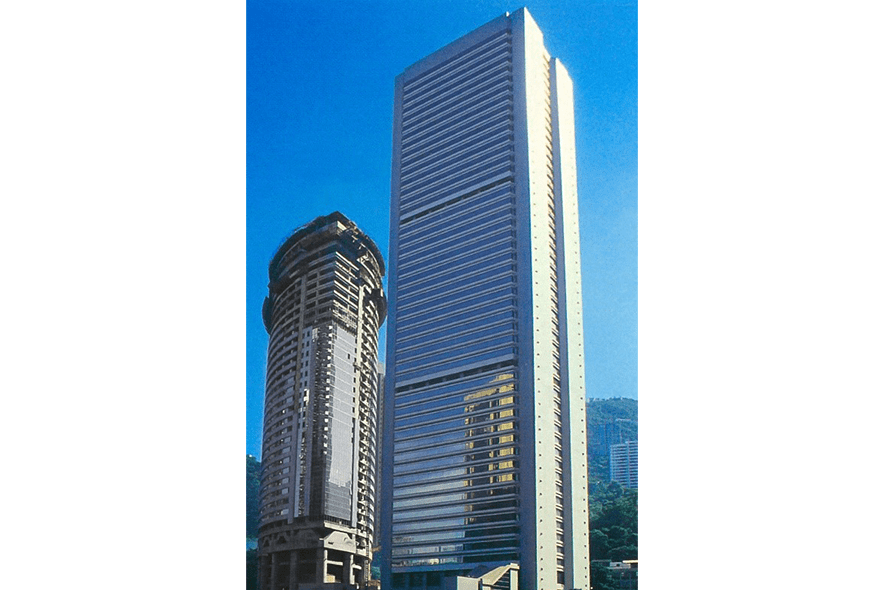 金鐘道政府合署高聳的灰色建築物，背景是藍天與翠綠山坡，這地標可作客製化退休禮物設計參考。