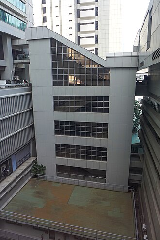 金鐘道政府合署的灰色大樓外觀，窗戶反射著光線，是製作獨一無二退休禮物公仔的場景靈感。