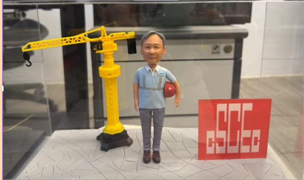 這款作品以 建築工程師 為主題設計，致敬多年專業堅守與匠心精神。 人物身穿工作制服，神情穩重親切，手持安全帽象徵責任與專業； 身後搭配迷你版 黃色吊塔模型 與 企業標誌牌， 完整重現建設現場的象徵性元素，極具職業代表意義。 底座以灰色地磚紋理設計，呼應工程基石的穩固與踏實， 整體封裝於透明展示盒中，既防塵又適合長久收藏。 前方金屬銘牌刻有「林利輝 榮休之樂」， 傳遞對敬業精神的尊敬與祝福。 此公仔特別適合作為 退休紀念、公務榮退、工程師表揚 或 建築業禮贈訂製， 以立體模型方式記錄職場成就， 讓每一道建築線條，化為人生精彩的印記。