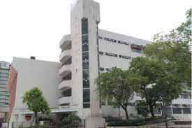 陳南昌紀念中學的米白色校舍建築，外牆可見圓弧形露台，周圍綠樹環繞，紀念學校的歷史與榮譽。