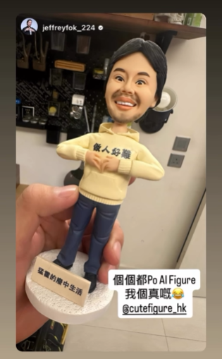 社群貼文截圖:左側手持一款迷你人像公仔,公仔留短髮與小鬍,穿奶油色衛衣與牛仔褲,雙臂交疊擺出自信姿勢;底座寫有中文標語。背景置入一張男子做「手心比心」手勢的照片作對比,右下角另有同一男子的搞怪表情小貼圖。畫面上方有中文字樣「霍哥真人 vs 公仔對比圖」,右側為帳號貼文介面與多個Hashtag。