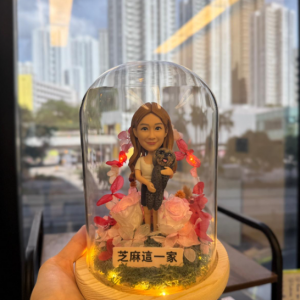 這款作品以 女生與愛寵相伴 為主題，將溫柔與快樂凝結在夢幻花園之中。 人物神態自然愉悅，懷中輕抱著一隻黑灰小貓， 可愛互動的姿態流露出真摯的情感連結。 底座以柔和的 乾燥花與苔綠草層 裝飾，粉紅花瓣與暖黃燈串交織成浪漫氛圍； 木質底座加上透明玻璃罩設計，既能防塵保護，亦增添典雅展示感。 前方刻有「芝麻這一家」字樣，象徵專屬家庭故事與幸福時光的定格。 此款公仔特別適合作為 寵物主題紀念、公仔擺設禮物、告白驚喜禮 或 家庭紀念作品， 讓人與寵的情感被永遠珍藏於光影與花香之間。