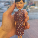 這款作品以 旗袍女性 為主題，展現東方女性的溫婉與高雅氣質。 人物神情柔和自信，髮髻盤起整齊端莊，微笑中流露出溫暖親切的風度。 她身穿一襲 深紫紅色碎花旗袍，細緻的花卉紋理與布料質感皆以手工上色刻畫， 完美重現傳統服飾的婉約之美與時代韻味。 腳踏紫色高跟鞋，立姿挺拔自然，整體氣場沉靜又不失優雅。 作品配有簡約白色底座，突顯人物主體之美，適合長久擺設與收藏。 此公仔特別適合作為 母親節禮物、長輩紀念公仔、榮退致敬禮或中式主題裝飾品， 以細緻雕工與藝術情感，傳遞敬意與感謝， 讓優雅姿態與溫柔笑容，永恆留存於歲月中。