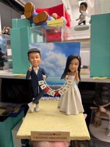 雙人婚禮公仔手拉日期旗串，沙灘背景與金色銘牌，結婚與週年紀念浪漫客製