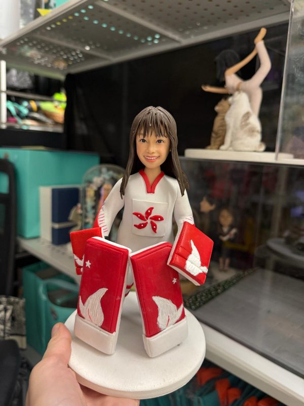 香港女子冰球守門員真人公仔穿著紅白代表隊球衣與護具，手持球桿面帶微笑，運動員紀念與退休客製禮物