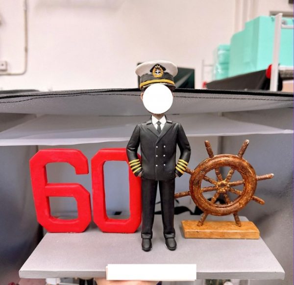 船長主題客製公仔：身穿黑色制服與肩章、戴船長帽的男子站在灰色底座中央，左側有紅色立體「60」字樣，右側擺放木質舵輪模型。