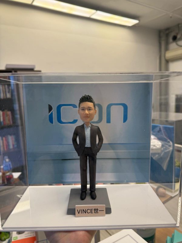 透明展示盒內的客製男士公仔，身著深色西裝與淺藍襯衫、雙手插袋站立，背板為「ICON」字樣，底座名牌寫著「VINCE 世一」