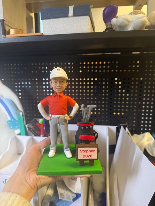 一個以高爾夫為主題的客製化人像公仔，人物神態自然，搭配球袋與草地底座，適合作為退休或紀念收藏。