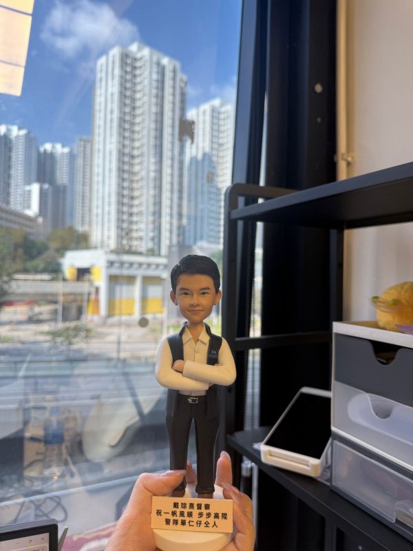 CUTEFIGUREHK 客製化香港警察人像公仔。公仔身穿白恤衫搭配深色背心，胸前佩戴「POLICE」字樣委任證，雙手交叉胸前展現自信。底座印有「戴琮熹督察 祝一帆風順 步步高陞 警隊華仁仔仝人」的專屬祝福語。這是一份專為紀律部隊人員升職或調職度身訂造的紀念禮物。