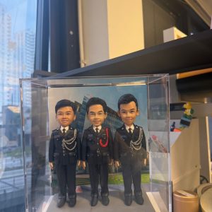 CUTEFIGUREHK 客製化三人紀律部隊人像公仔，三位男主角身穿整齊警察制服並佩戴精緻飾繩，背後配以總部大樓背景，並裝在透明亞加力展示盒中，是專為同袍升職、調職或退休訂製的專屬紀念禮物。