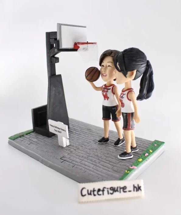 送給Cherry的生日禮物人像公仔。兩位穿著同款球衣的女孩站在微縮籃球場上，其中一位拿著籃球，旁邊的名牌寫著生日祝福。