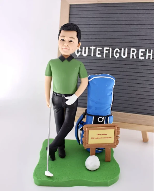 一個高爾夫球員的榮休禮物人像公仔。他身穿綠色上衣，倚靠著藍色高爾夫球袋，旁邊的木牌寫著祝福語「Life begins at retirement!」。
